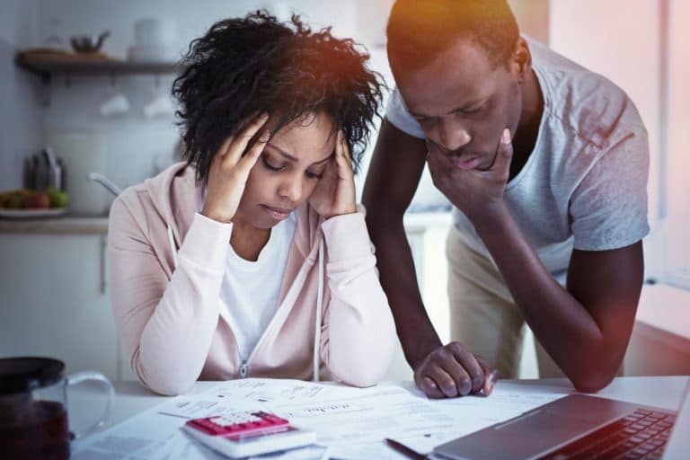 A couple stressed and reviewing papers on their kitchen table.